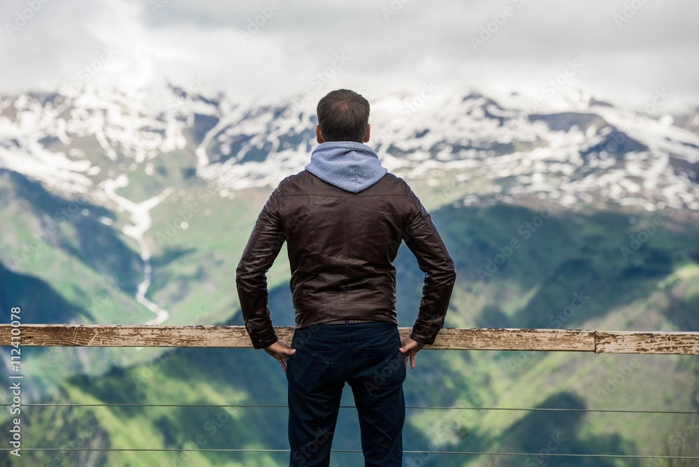 Wall mural summer vacation at mountains. young man standing in a mountain meadow.