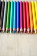 Fototapeta premium Color Pencils on wood texture. Macro shot of colorful pencils. Vertical view of pencils.