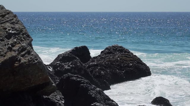 View of waves hitting rocks on a sunny day at Point Dume