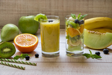 Fruit smootie and salad in 2 glasses.