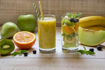 Fruit smootie and salad in 2 glasses.