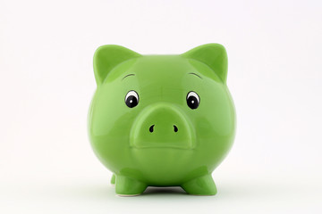 Grünes Sparschwein steht frontal zur Kamera auf weißem Hintergrund