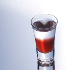 Colorful layered shot isolated on white gray gradient background with reflection. Alcohol shooter