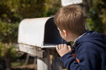 School boy opening a post box and checking mail. Kid waiting for a letter, checking correspondence...