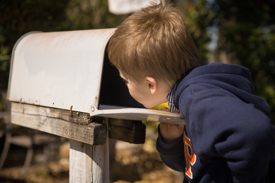 School Boy Opening A Post Box And Checking Mail. Kid Waiting For A Letter, Checking Correspondence And Looking Into The In The Metal Mailbox.