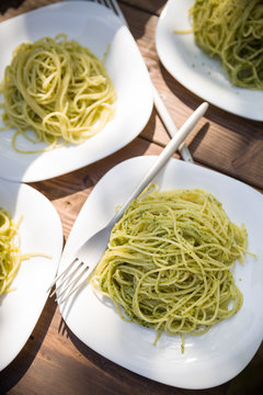 Delicious Italian pasta with green pesto. Spaghetti with homemade basil pesto sauce. Healthy dinner or lunch. Homemade food on wooden table background