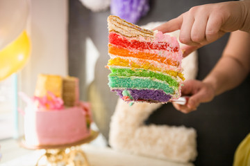 People eating delicious rainbow cake. Homemade colorful cake for birthday party. Hands with piece...