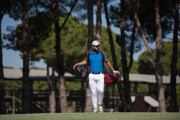 golf player walking and carrying bag