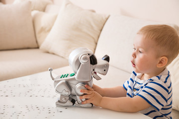 Adorable toddler boy playing with interactive toy. Child with toy robot dog. indoors. Activities for small children. Communication and digital concept.