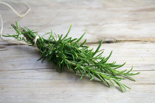 bunch of rosemary herb, Rosmarinus officinalis, on a rustic wooden board