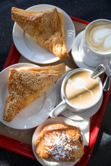 Coffe break at work. Top view on puff pastry and coffee cups on the table outdoors. Croissants and...