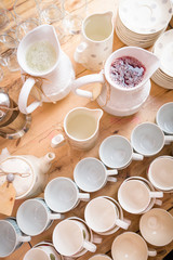 Rows of cups and jars with homemade lemonade on the wooden table. Table setting for party. glassware on the table. Cups and glasses for celebration.