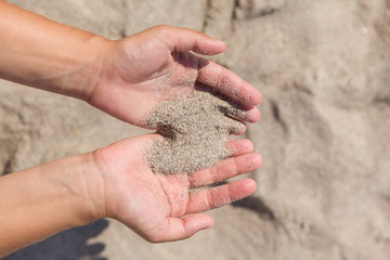 Sand running through female hands.Young woman with sand in her hands. Sand as