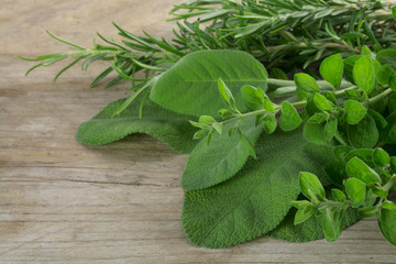 fresh Mediterranean herbs, oregano, rosemary and sage, on a rustic wooden table