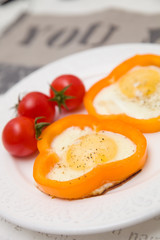 Fried organic eggs inside orange paprica rings. Eggs served with tomatos and paprica. Healthy breakfast or snack. Protein meal. Healthy eating.