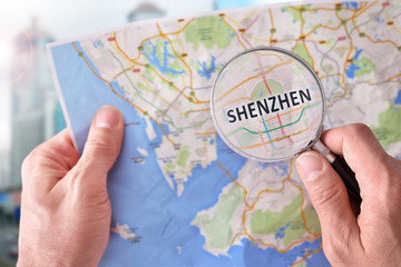 Man consulting a map of Shenzhen with a magnifying glass