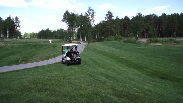 A man rides in a car on a Golf course. View