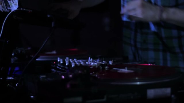DJ scratching vinyl records and mixing on the Decks at a disco in Nightclub 3