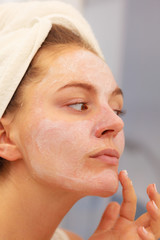 Woman applying mask cream on face in bathroom