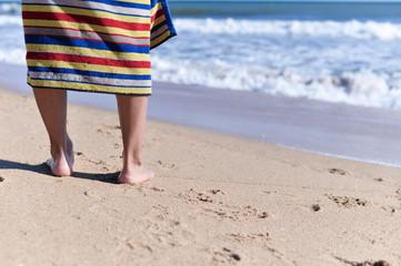 Person wearing towel walking along sand beach, closeup ol legs. sunny background outdoors