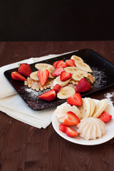 Waffles with fresh strawberries and bananas on rustic wooden background. Top view