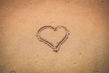 Love heart drawn on sand background