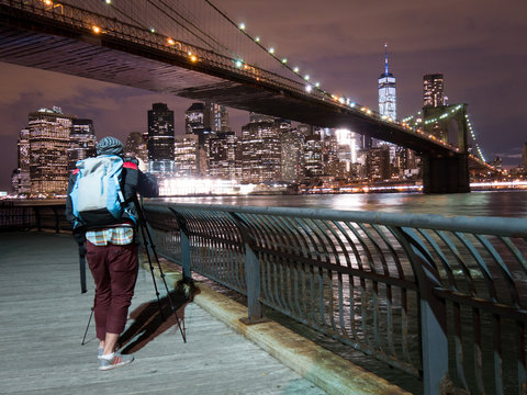Person taking picture from Brooklyn Bridge with WTC at Night