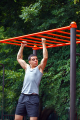 Muscular man doing pull-ups on horizontal bar