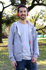 Young man listening to music with headphones in park.