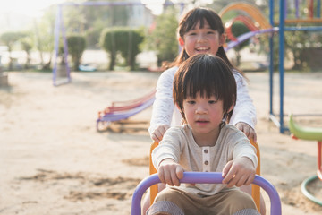 Fototapeta na wymiar Cute asian child riding seesaw board at the playground