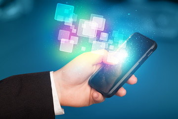 Hand holding smart phone with abstract glowing squares