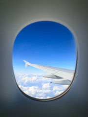 Fototapeta na wymiar Cloud and wing seen through airplane window