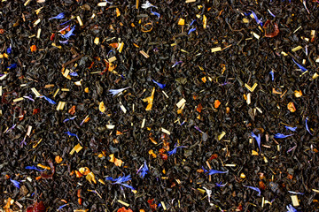 Dry tea with fruit and flower petals as background
