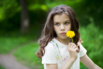 Little girl smelling a yellow dandelion