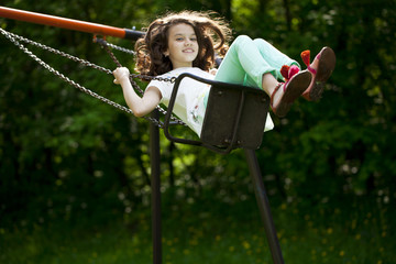 Little girl on a swing in the summer park