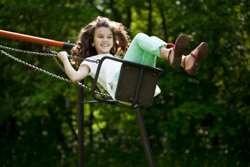 Little girl on a swing in the summer park
