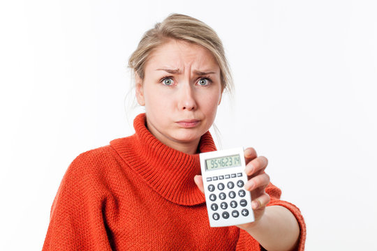 Worried Young Blond Woman Pouting, Holding A Calculator, Losing Money