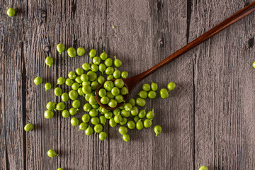 peas on a wood table with spoon