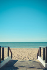 Fototapeta na wymiar Sandy beach with wooden walkway on sunny day background