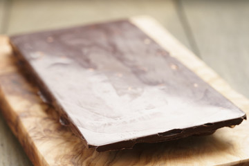 whole homemade bar of chocolate with cashew nuts, on wooden board shalow focus