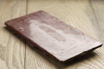 whole homemade bar of chocolate with cashew nuts, on wooden board shalow focus