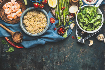 Cooked white quinoa in bowl with fresh vegetables cooking ingredients on dark rustic background, top view, border. Superfood , healthy eating or vegetarian food concept.