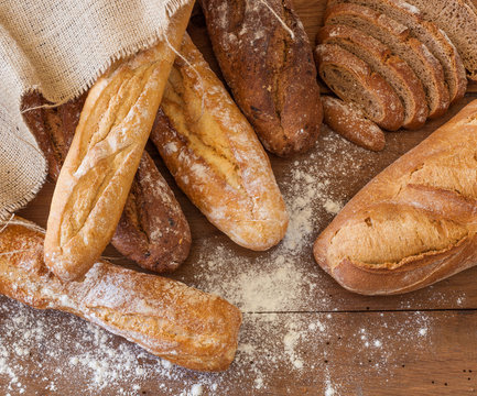 Fresh rustic bread on dark wood background with flour - Powered by Adobe
