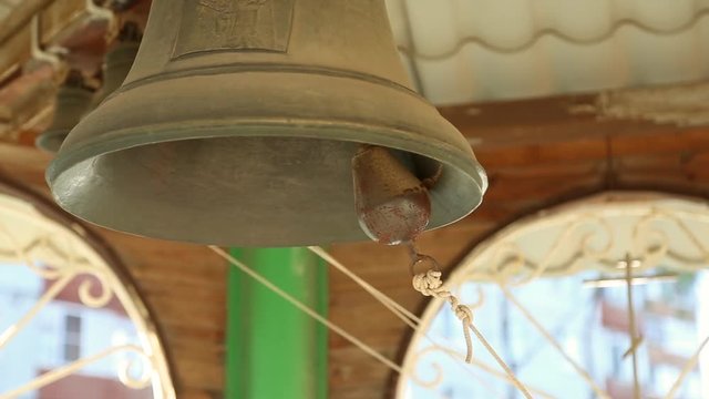 The church bells are ringing in the chapel in Russia, the bell-ringer pulls the rope
