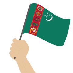Hand holding and raising the national flag of Turkmenistan