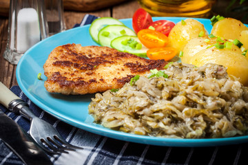Fried pork chop, baked potatoes and fried young cabbage.