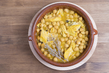 Close-up of hot soup with chickpeas and cod in bowl on table.From above