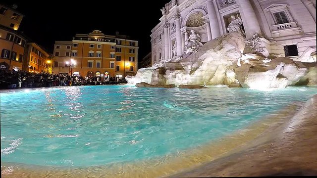 Tourists visiting and posing in the front of the Trevi fountain (Fontana di Trevi), one of the major sights of Rome