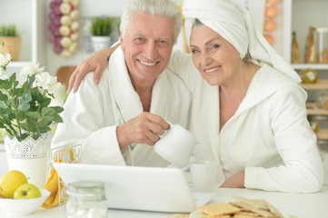 senior couple in a bathrobes with laptop
