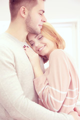 Fototapeta premium Young couple in love embracing beside the window